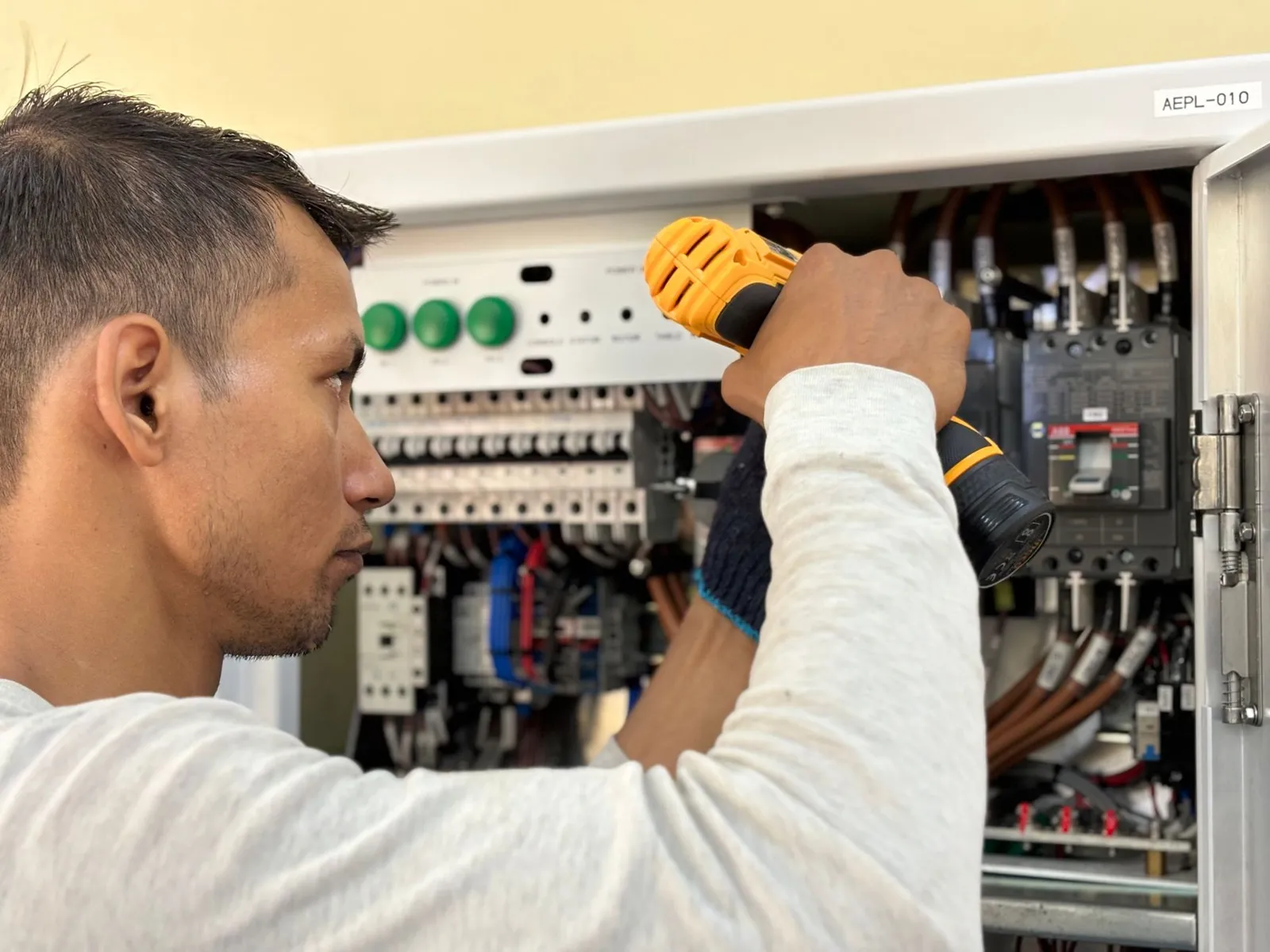 Eletricista usando parafusadeira num quadro de disjuntores