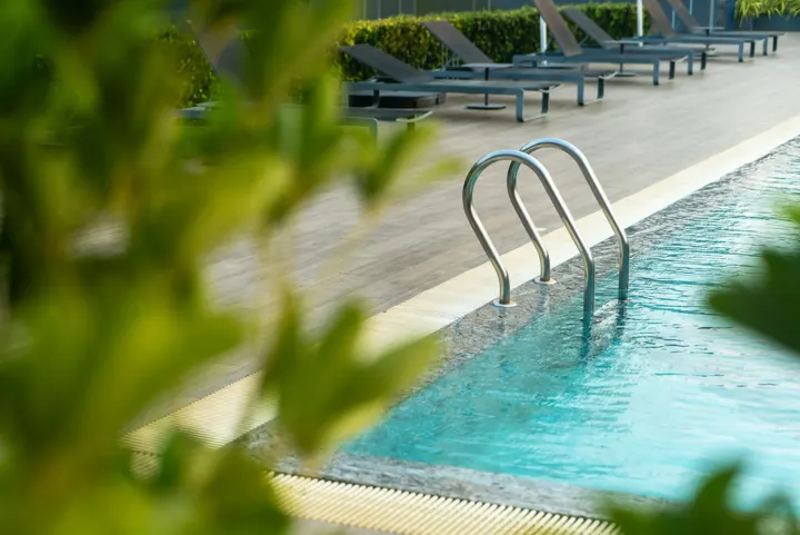 Piscina com escada de inox e plantas na borda