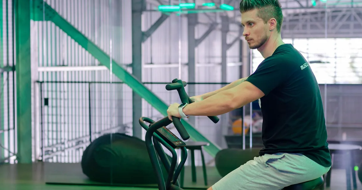 Homem pedalando bicicleta de ar em treino intervalado na academia